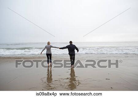 Stock Photography - Mature couple holding hands on beach. Fotosearch