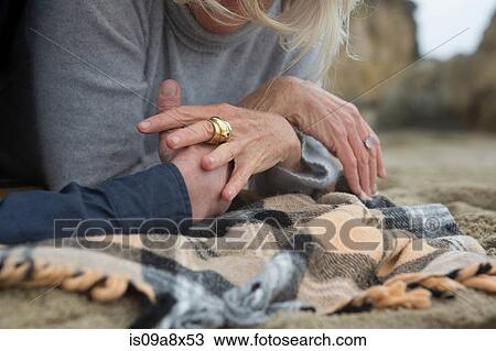 Mature couple lying on beach holding hands, close-up View Large Photo Image Stock Image - Mature couple lying on beach holding hands, close-up. Fotosearch