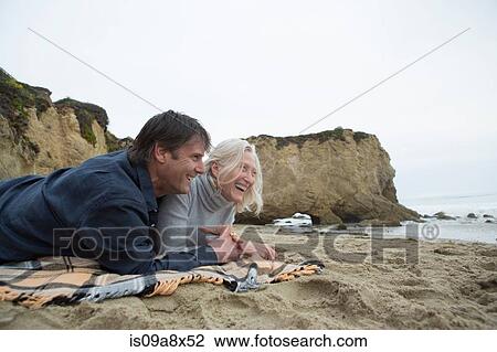 Mature couple lying on beach, laughing View Large Photo Image Stock Image - Mature couple lying on beach, laughing. Fotosearch