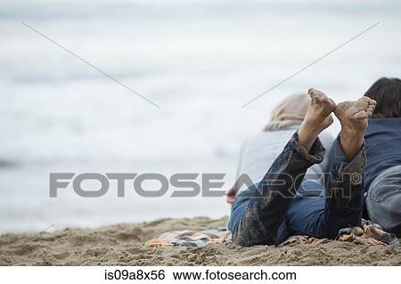 Mature couple lying on beach looking at sea View Large Photo Image Stock Photograph - Mature couple lying on beach looking at sea. Fotosearch