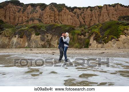 Stock Photograph - Mature couple standing in sea kissing. Fotosearch