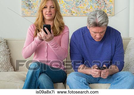 Stock Image - Mature couple using cell phones. Fotosearch