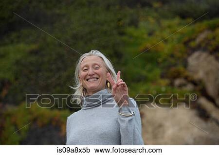 Stock Image - Mature woman making victory sign. Fotosearch