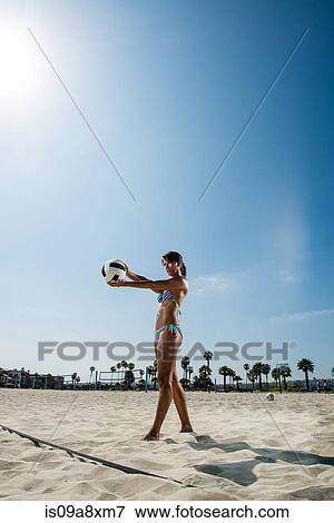 Stock Photo - Mature woman serving in beach volleyball. Fotosearch