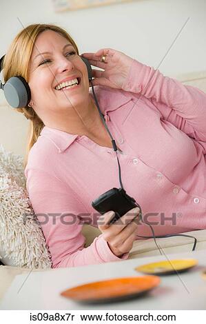 Stock Photography - Mature woman wearing headphones, smiling. Fotosearch