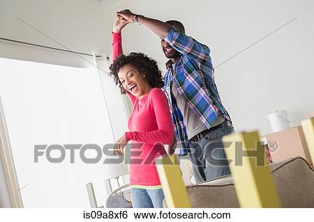 Stock Photograph - Mid adult couple dancing in new home. Fotosearch