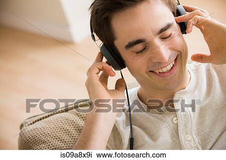 Stock Image - Mid adult man wearing headphones. Fotosearch