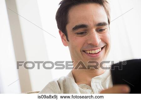 Stock Image - Mid adult man with cell phone, smiling. Fotosearch