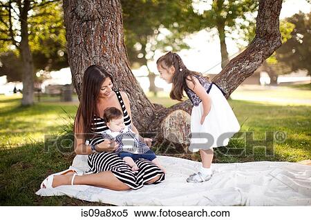 Stock Photography - Mother and two daughters on picnic blanket. Fotosearch