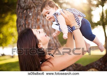 Mother holding up baby daughter View Large Photo Image Stock Photograph - Mother holding up baby daughter. Fotosearch