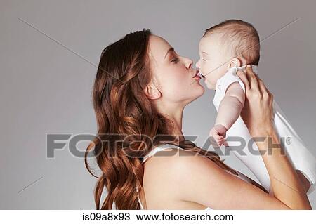 Stock Image - Mother kissing baby daughter. Fotosearch