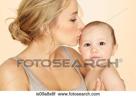 Stock Image - Mother kissing baby son on head. Fotosearch