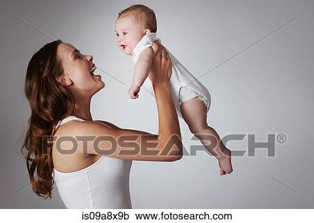 Stock Image - Mother lifting baby daughter. Fotosearch