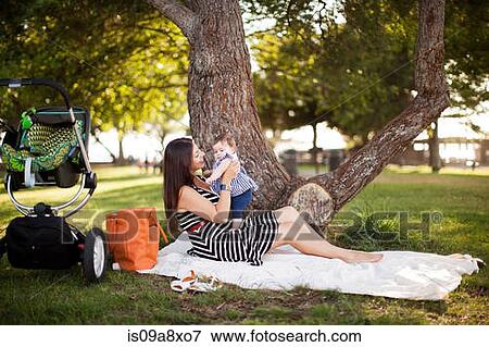 Mother sitting on picnic blanket with baby daughter View Large Photo Image Stock Photo - Mother sitting on picnic blanket with baby daughter. Fotosearch