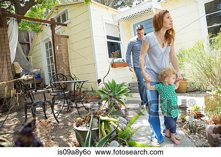 Picture - Parents & child walking in the backyard. Fotosearch