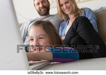 Stock Image - Parents looking at child using laptop. Fotosearch