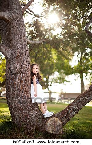 Stock Image - Portrait of girl standing on tree trunk. Fotosearch
