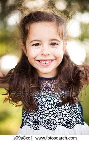 Stock Image - Portrait of girl with long brown hair looking at camera. Fotosearch