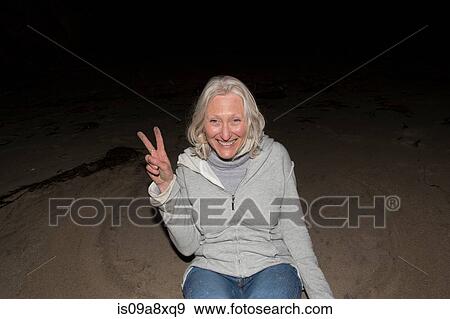 Stock Photo - Portrait of mature woman making victory sign. Fotosearch