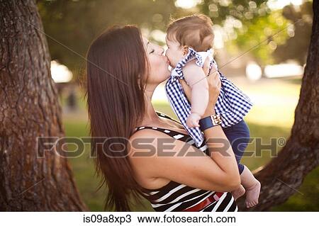 Stock Image - Portrait of mother kissing baby daughter. Fotosearch