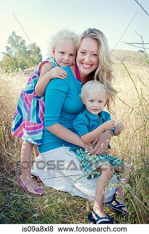 Stock Photo - Portrait of mother with son and daughter in field. Fotosearch