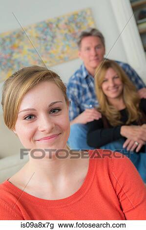 Stock Image - Portrait of teenage girl with parents in background. Fotosearch