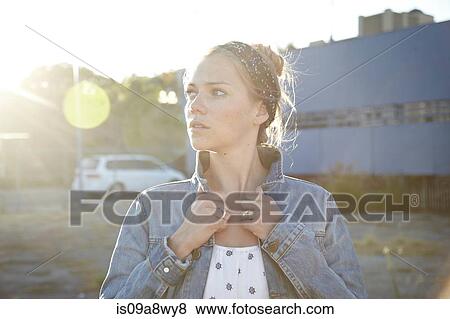 Portrait of woman holding jacket collar in industrial district View Large Photo Image Stock Photo - Portrait of woman holding jacket collar in industrial district. Fotosearch