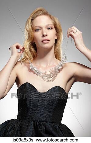 Stock Photograph - Portrait of woman putting on necklace. Fotosearch