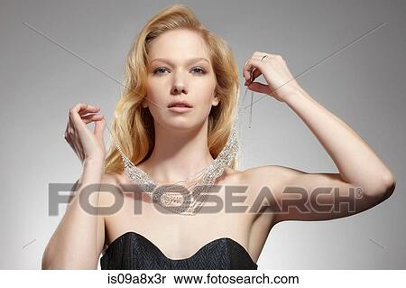 Portrait of woman putting on necklace View Large Photo Image Stock Photography - Portrait of woman putting on necklace. Fotosearch
