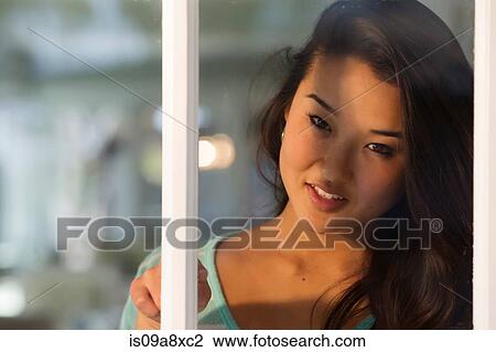 Portrait of young woman looking through window smiling View Large Photo Image Stock Image - Portrait of young woman looking through window smiling. Fotosearch