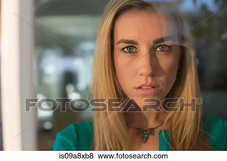 Portrait of young woman staring through window View Large Photo Image Stock Photo - Portrait of young woman staring through window. Fotosearch