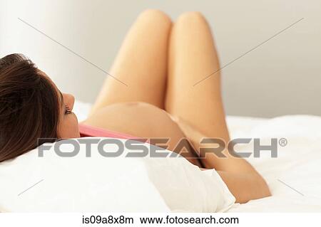 Picture - Pregnant woman lying on bed. Fotosearch