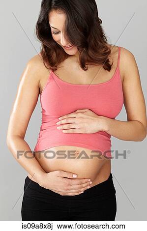 Stock Image - Pregnant woman touching stomach. Fotosearch