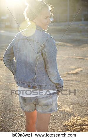 Stock Image - Rear view of woman standing in industrial area. Fotosearch