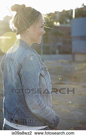 Stock Image - Rear view of woman standing in industrial area. Fotosearch