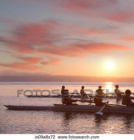 Stock Image - Seven people rowing at sunset. Fotosearch