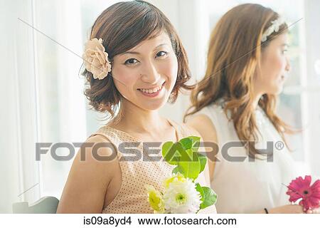 Picture - Smiling woman with flower looking at camera. Fotosearch