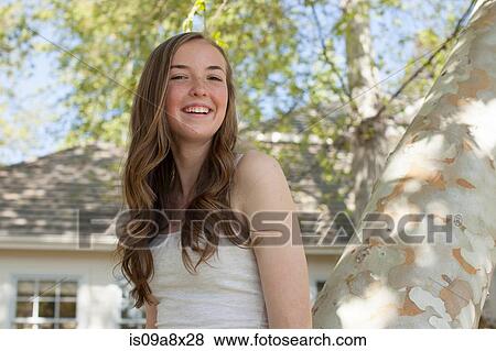 Stock Photo - Teenage girl in tree, looking at camera. Fotosearch