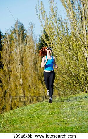 Stock Image - Teenage girl jogging in park. Fotosearch