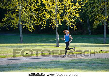 Stock Image - Teenage girl jogging in park. Fotosearch