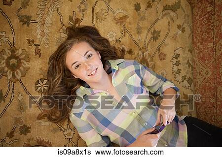 Teenage girl lying on floor with cell phone View Large Photo Image Stock Photograph - Teenage girl lying on floor with cell phone. Fotosearch