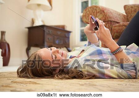 Teenage girl lying on floor with cell phone View Large Photo Image Stock Photograph - Teenage girl lying on floor with cell phone. Fotosearch