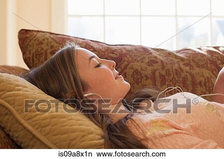 Teenage girl lying on sofa with earphones View Large Photo Image Picture - Teenage girl lying on sofa with earphones. Fotosearch