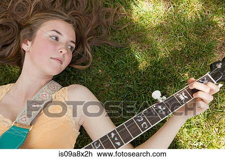 Stock Image - Teenage girl playing banjo on grass, overhead view. Fotosearch