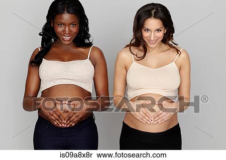 Stock Photography - Two pregnant women making heart shapes with hands on stomachs. Fotosearch