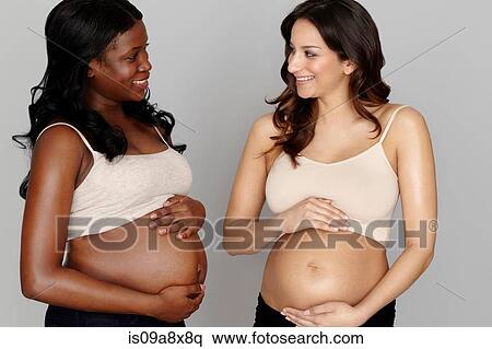 Stock Photography - Two pregnant women touching stomachs. Fotosearch