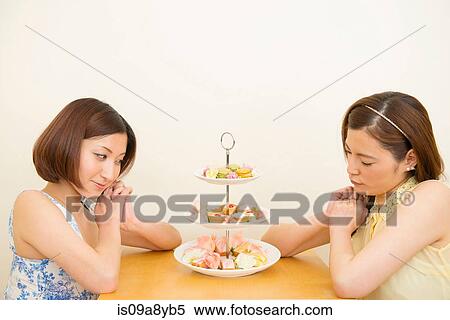 Stock Photography - Two women looking at assortment of confectioneries. Fotosearch