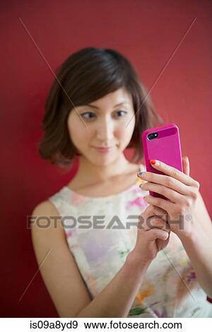 Woman against red wall using mobile phone View Large Photo Image Stock Photo - Woman against red wall using mobile phone. Fotosearch