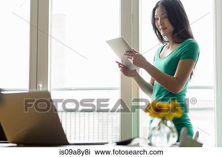 Woman holding digital tablet looking at laptop View Large Photo Image Stock Image - Woman holding digital tablet looking at laptop. Fotosearch