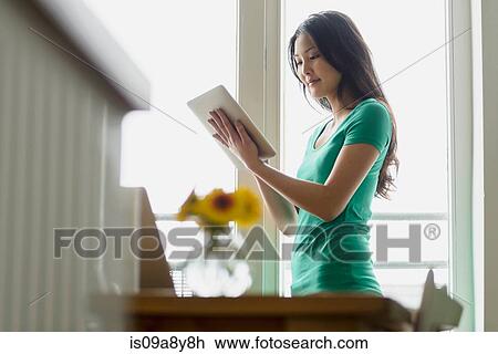 Stock Image - Woman holding up and using digital tablet. Fotosearch